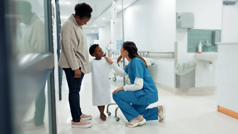 Mother and child talking to paediatrician in hospital corridor