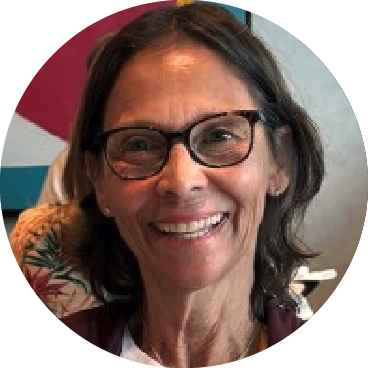Camille Cappiello smiling, wearing glasses, with a colorful background. 
